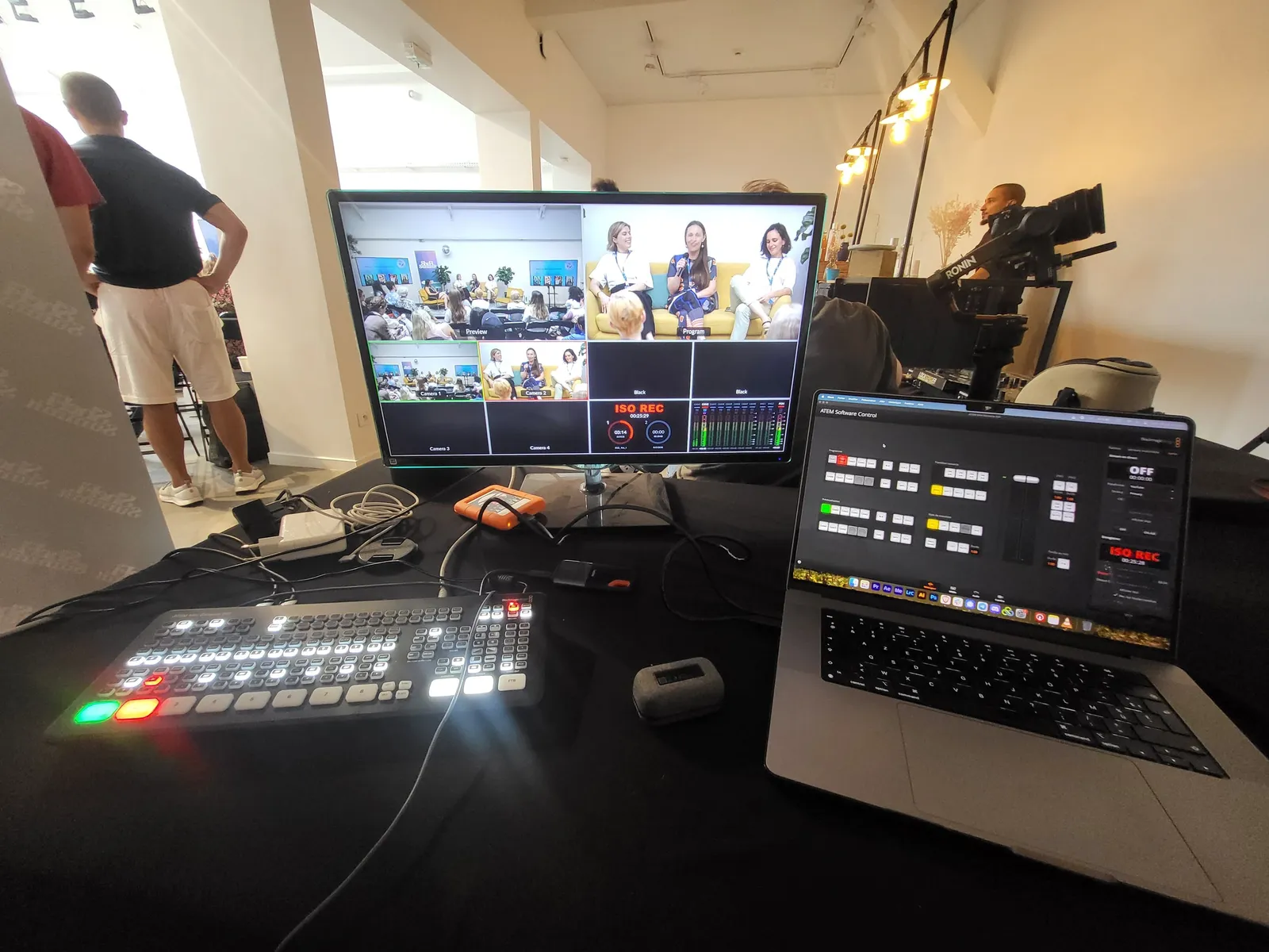 A broadcast control desk with multiple video feeds on screen.
