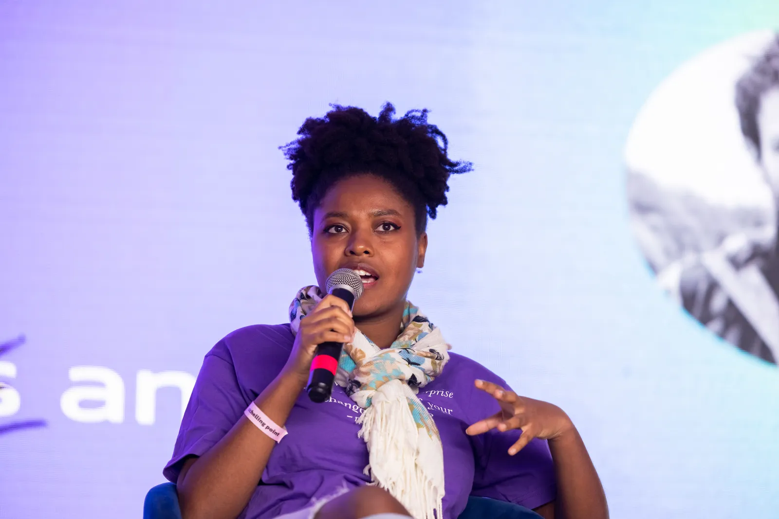 A panelist speaking into a microphone on stage.