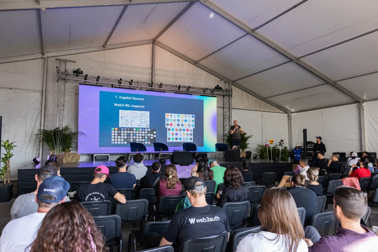 A large event tent with a speaker presenting to a seated audience.